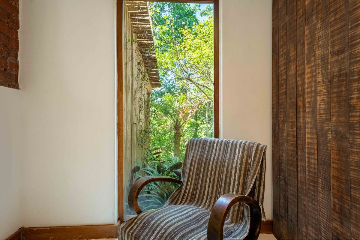 A cozy living space featuring a large floor-to-ceiling window with garden views, accented by exposed brick and vertical timber wall paneling.