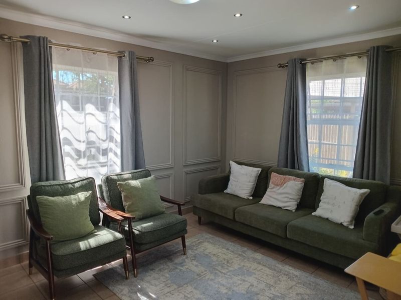 A well-maintained living room featuring decorative wainscoting, recessed downlighting, and tiled flooring, offering a comfortable and classic aesthetic.