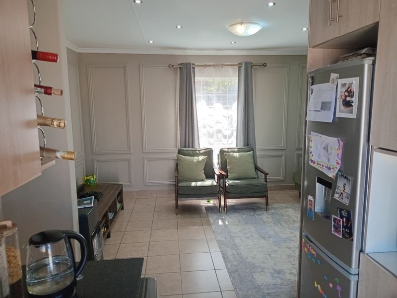 Open-plan living area featuring tiled flooring, decorative wall paneling, and recessed lighting, seamlessly connecting to the kitchen space.