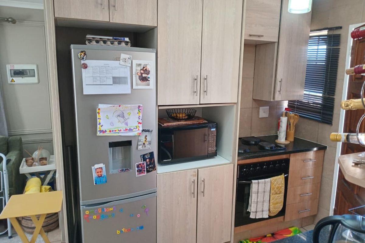 A functional kitchen featuring light wood-finish cabinetry, granite countertops, a built-in oven, and an electric hob with a tiled backsplash.