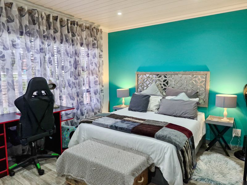 A well-maintained bedroom featuring timber-look flooring, a tongue and groove ceiling, and recessed downlighting, creating a comfortable and functional living space.