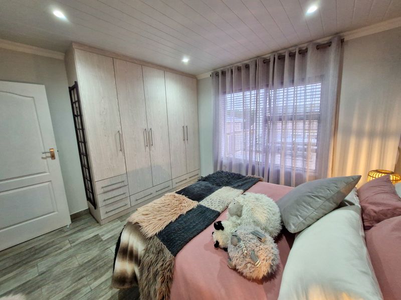 A well-maintained bedroom featuring built-in wardrobes, recessed downlighting, and modern timber-look tile flooring.