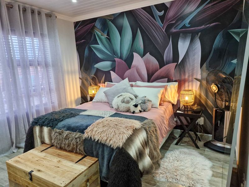 A well-maintained bedroom featuring tiled flooring, a tongue and groove ceiling, and a decorative feature wall.