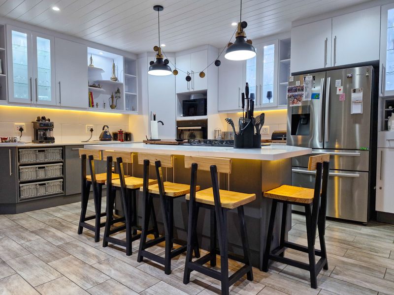 Modern kitchen featuring a central island with breakfast bar seating, sleek cabinetry, integrated appliances, and stylish pendant lighting.