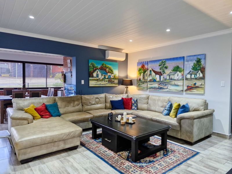 A well-maintained living room featuring tiled flooring, a tongue and groove ceiling with recessed lighting, and a wall-mounted split system air conditioner.