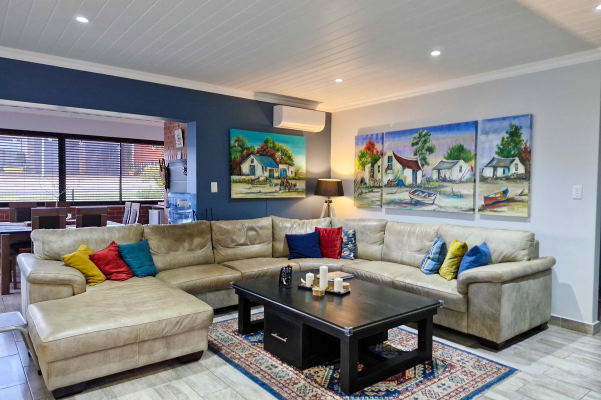 A well-maintained living room featuring tiled flooring, a tongue and groove ceiling with recessed lighting, and a wall-mounted split system air conditioner.
