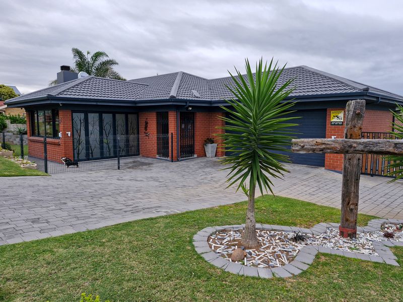 Front view of a well-maintained brick house featuring a paved driveway, integrated garage, and modern bi-fold doors leading to the interior.