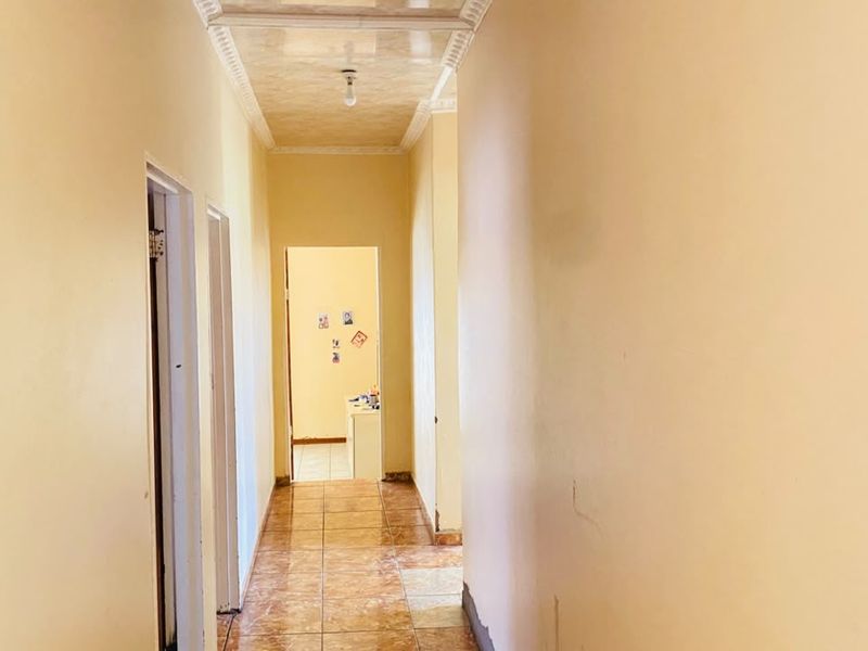 A vacant interior hallway featuring tiled flooring and a coved ceiling, providing access to adjacent rooms.