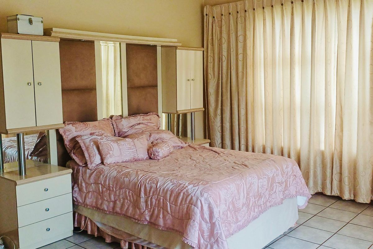 A bedroom featuring tiled flooring and a built-in headboard unit with integrated storage, complemented by floor-to-ceiling curtains.