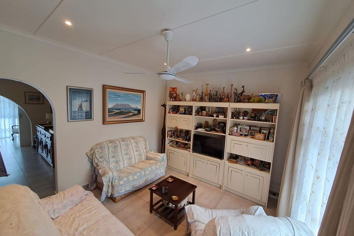 A comfortable living room featuring tiled flooring, a ceiling fan, and a built-in media storage unit, with an arched doorway leading to an adjacent space.