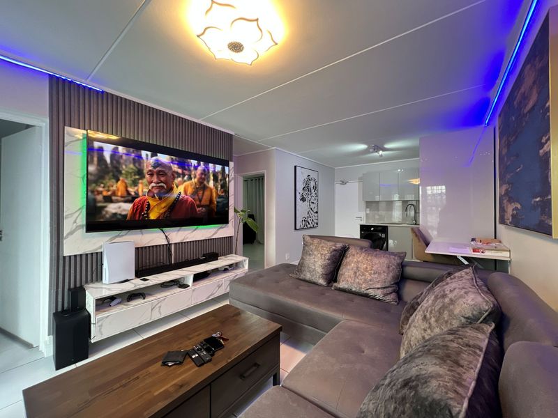 Modern open-plan living area featuring a contemporary slatted feature wall, integrated kitchen cabinetry, and sleek tiled flooring throughout the space.