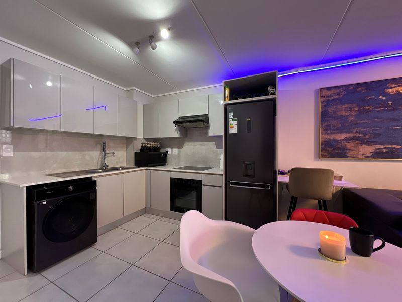 Modern kitchen featuring sleek cabinetry, integrated appliances, a built-in washing machine, and tiled flooring, creating a functional and contemporary cooking space.