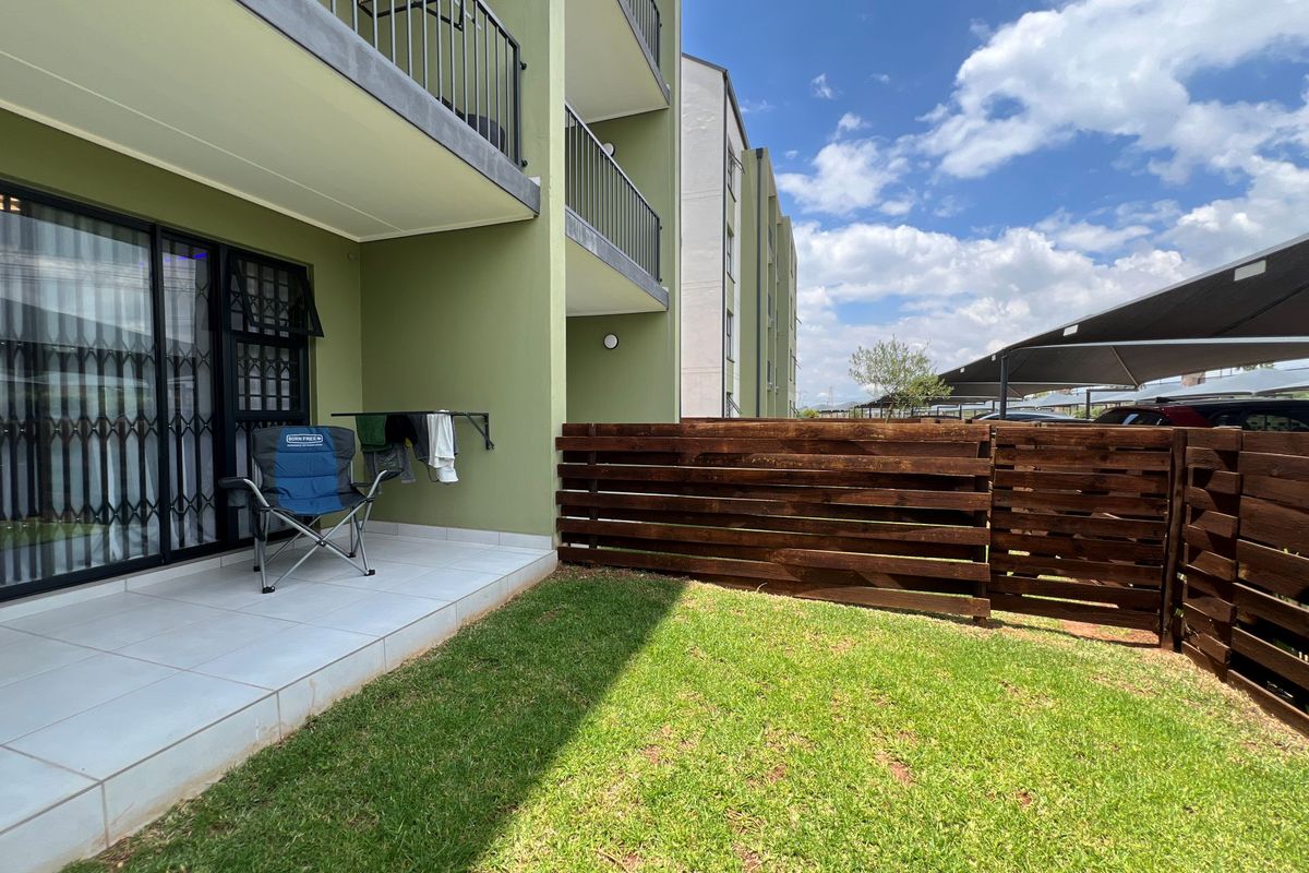 Ground floor apartment featuring a private tiled patio, small lawn area, and timber privacy screening, providing a functional outdoor space.