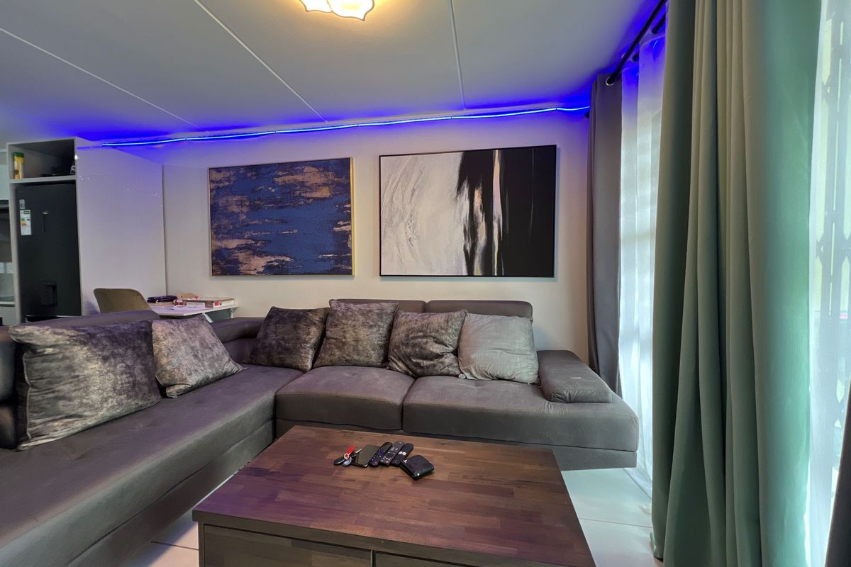 A comfortable living room featuring tiled flooring, modern recessed ceiling lighting, and large windows with curtain tracks.