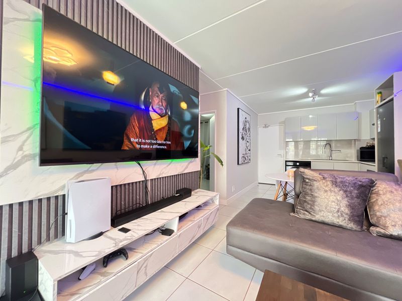 Modern open-plan living area featuring a slatted feature wall with integrated media console and a sleek, contemporary kitchen with gloss cabinetry.