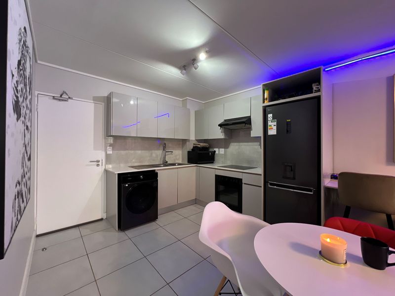 Modern kitchen featuring sleek cabinetry, stone countertops, integrated oven, extractor fan, and tiled flooring, providing a functional and contemporary cooking space.