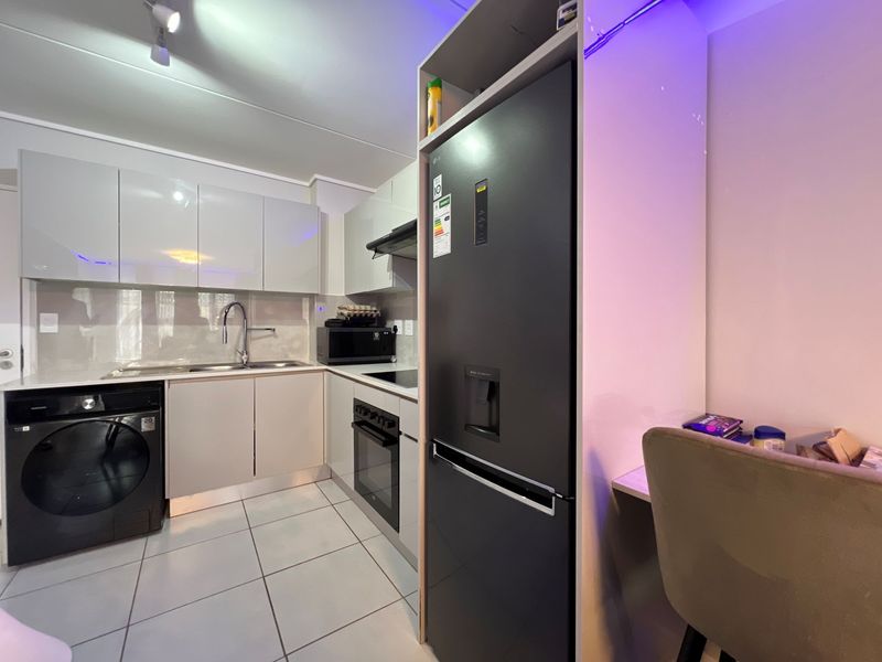 Modern kitchen featuring glossy cabinetry, built-in oven, hob, extractor fan, and tiled flooring, with integrated space for a refrigerator.