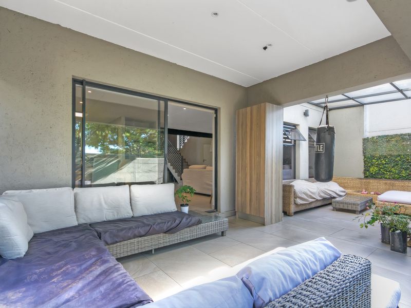 A spacious covered patio area featuring tiled flooring, recessed ceiling lighting, and a built-in storage cabinet, providing a seamless transition to the interior living space.