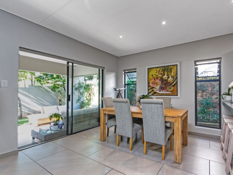 Open plan dining area featuring large format floor tiles, recessed downlighting, and sliding glass doors providing seamless access to the outdoor patio.