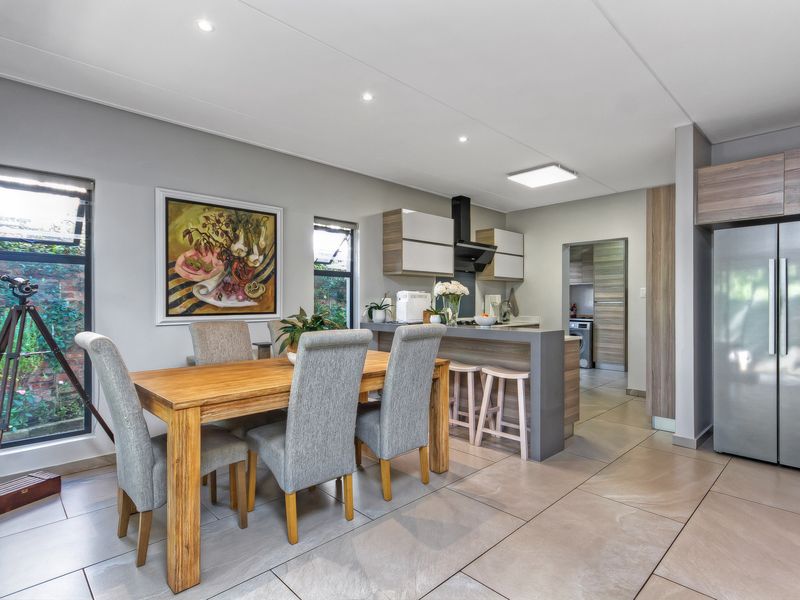Open-plan kitchen and dining area featuring modern cabinetry, a breakfast bar, tiled flooring, and recessed lighting, with an adjacent scullery.