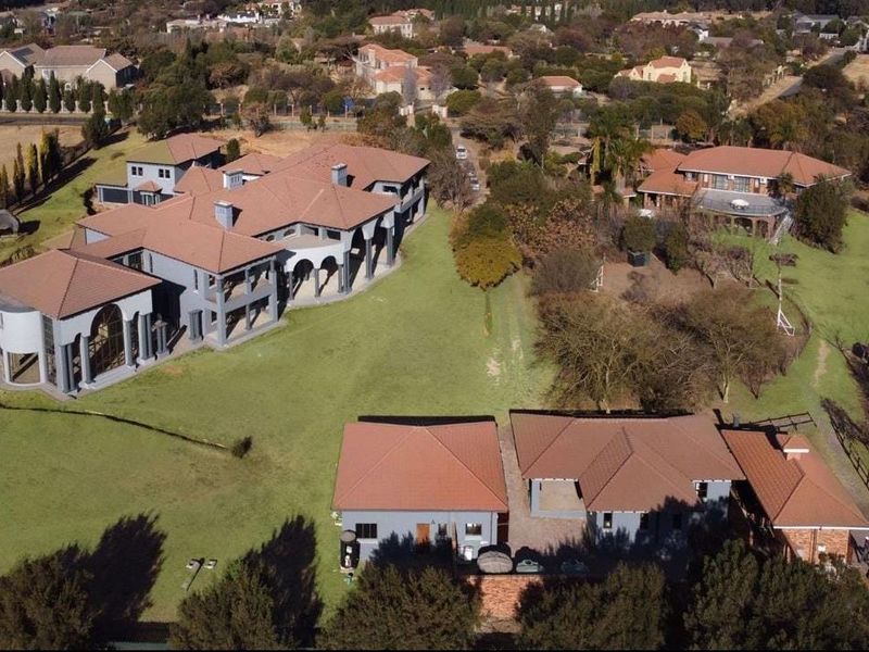 Aerial view of a large residential estate featuring multiple buildings with terracotta tile roofs, expansive lawns, and established landscaping.