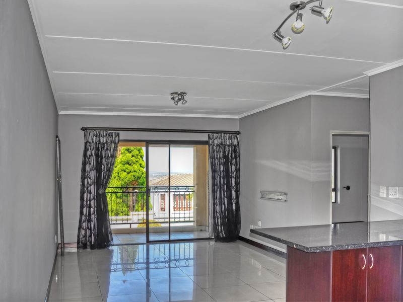Spacious open-plan living area featuring polished tile flooring, a kitchen island, and a sliding glass door leading to a private balcony.