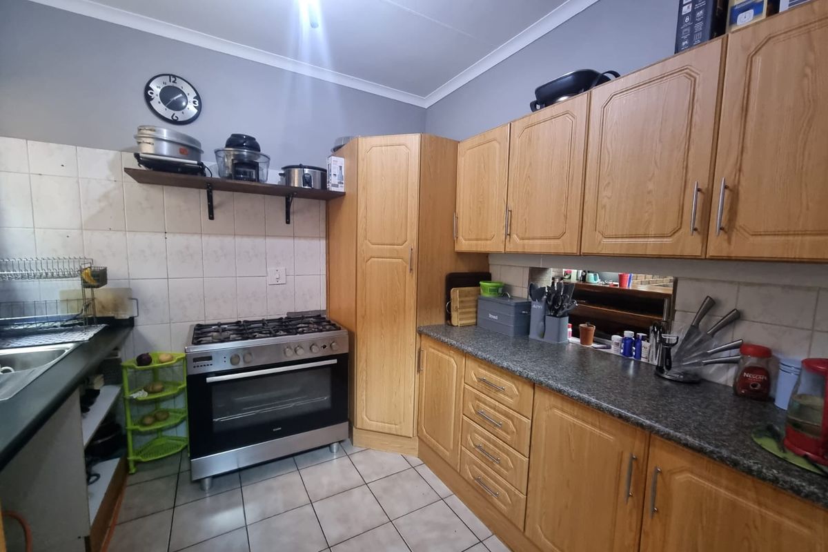 A functional kitchen featuring wood-look cabinetry, granite-style countertops, tiled splashbacks, and a built-in gas stove with oven.