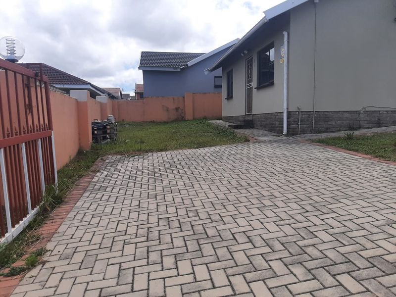 Front exterior view of the property featuring a paved driveway, perimeter boundary wall, and metal entrance gate.