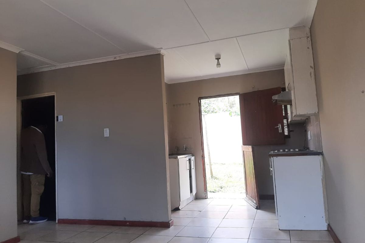 A basic, functional kitchen area featuring tiled flooring, built-in cabinetry, and direct access to the exterior, offering potential for modernization and cosmetic updates.