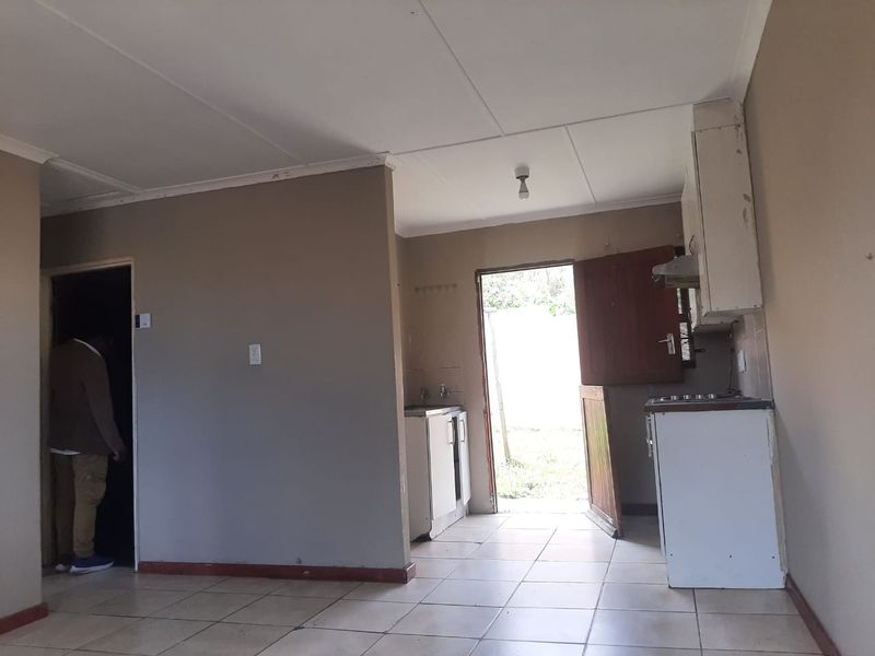 A basic, functional kitchen area featuring tiled flooring, built-in cabinetry, and direct access to the exterior, offering potential for modernization and cosmetic updates.
