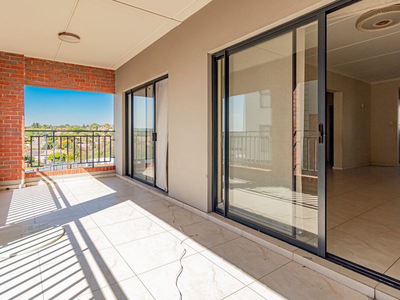 Spacious covered balcony featuring tiled flooring, brick accents, and sliding glass doors providing seamless access to the interior living area.