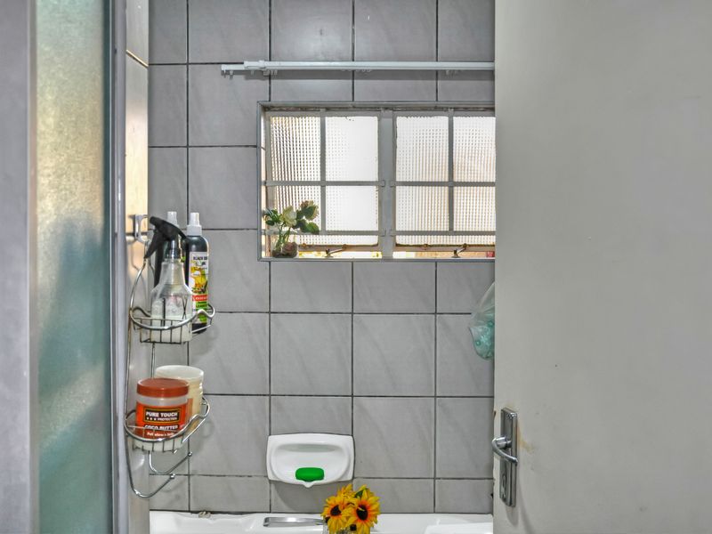 A functional bathroom featuring tiled walls, a shower enclosure, and an obscured glass window providing natural light.