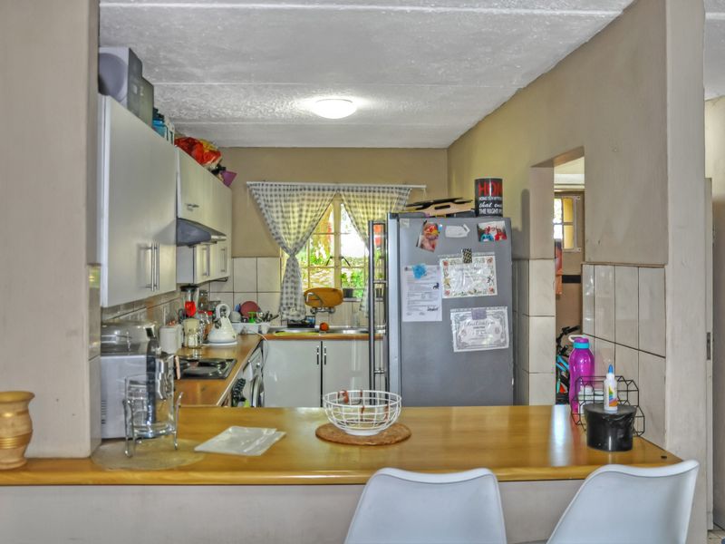 A functional kitchen featuring built-in cabinetry, a breakfast bar, and a tiled backsplash, offering a practical layout with potential for modern updates.