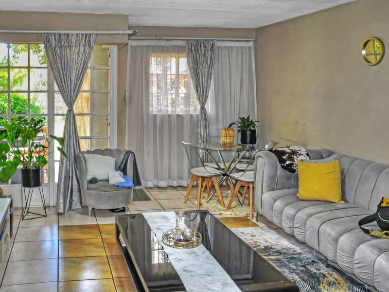 A living room featuring tiled flooring, a large window, and a french door leading to an outdoor area.