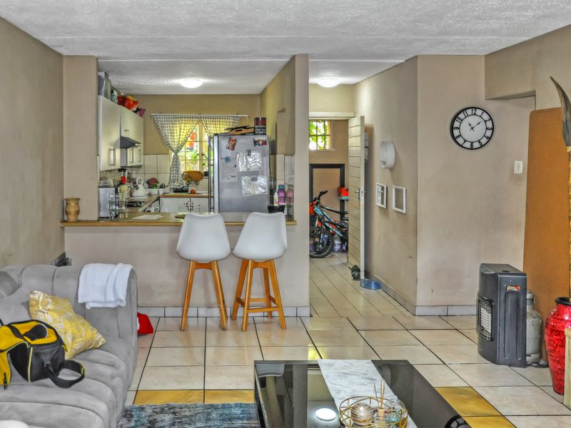 Open-plan living area featuring a kitchen with breakfast bar, tiled flooring throughout, and direct access to a utility space.