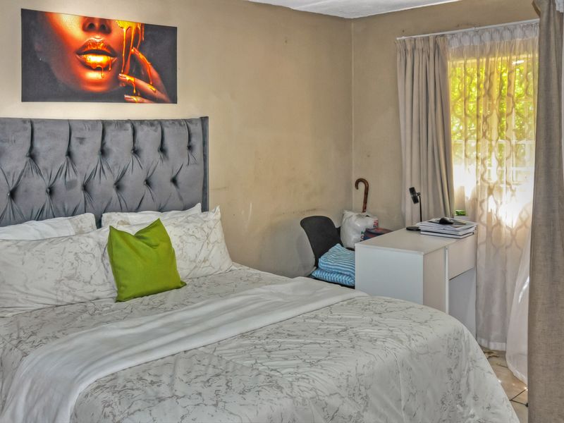 A bedroom featuring neutral wall tones and natural light through window treatments, requiring minor cosmetic updates to improve the overall finish.