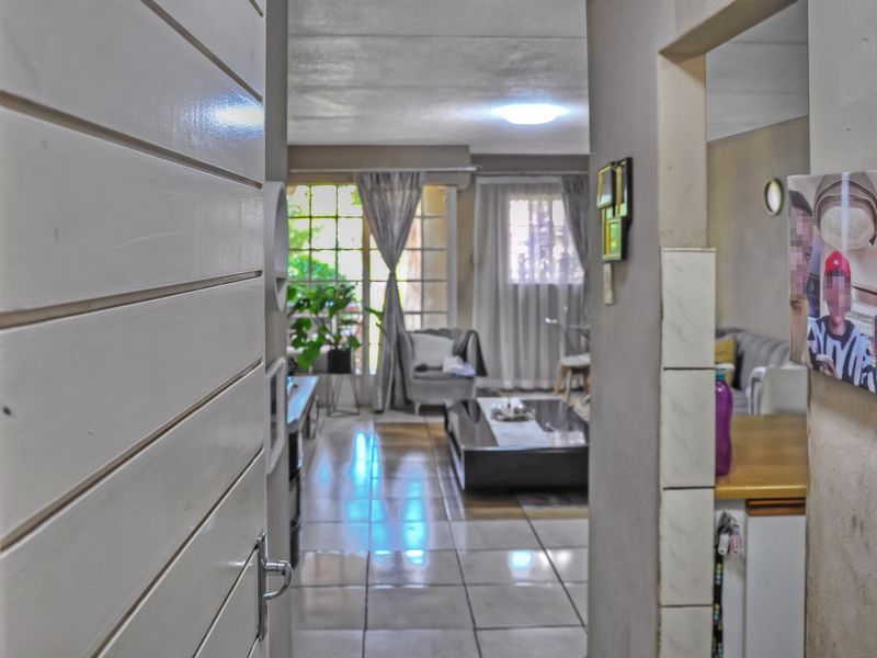 View from the entrance into an open-plan living area featuring tiled flooring and natural light through a sliding glass door.