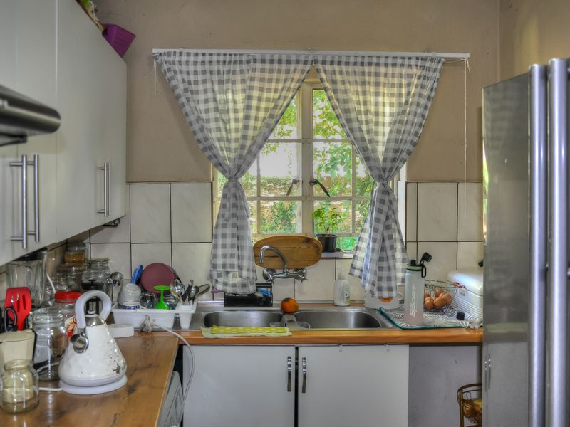 A compact kitchen featuring a double basin sink, laminate countertops, tiled splashbacks, and built-in cabinetry with an extractor fan.