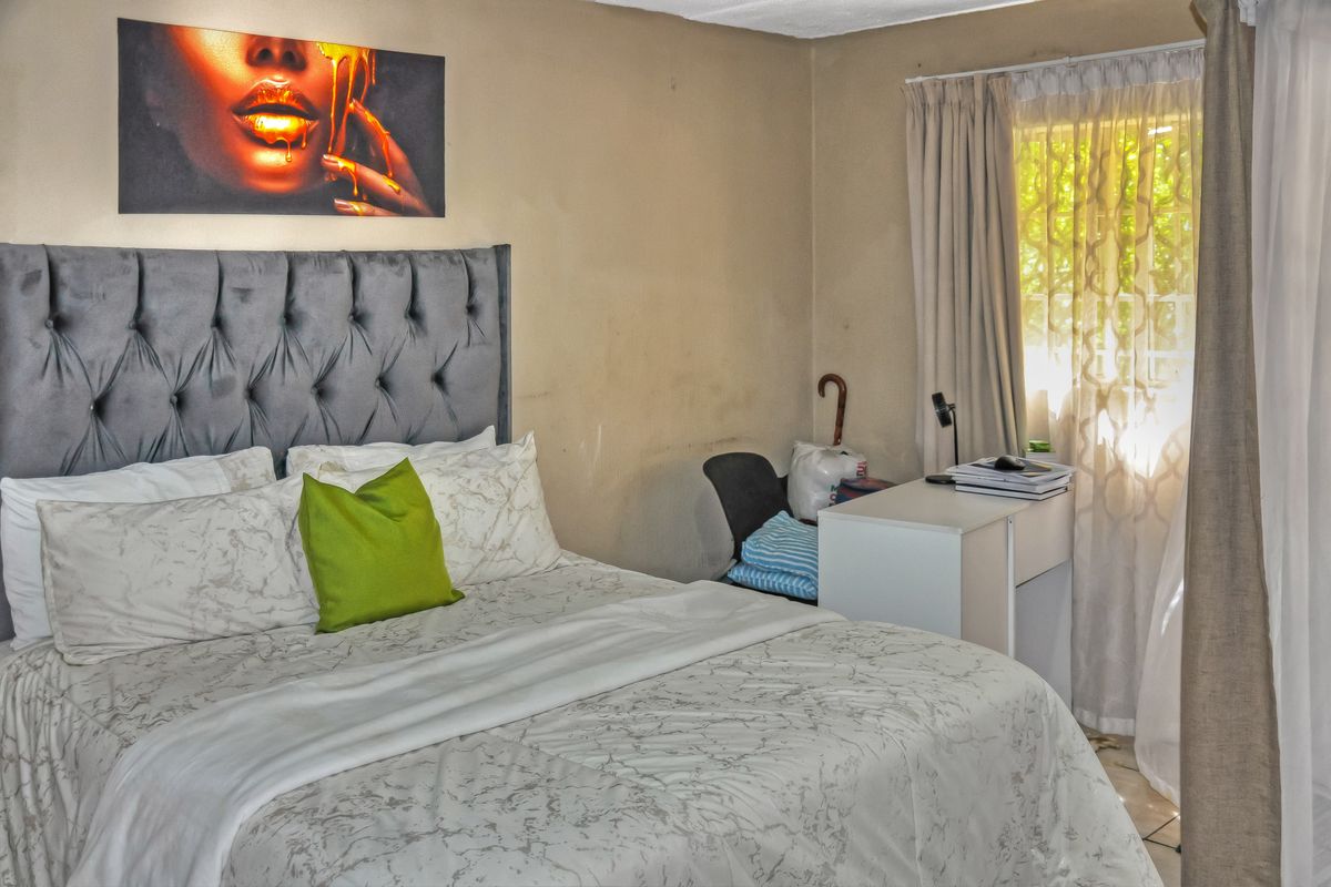 A bedroom featuring neutral wall tones and natural light through window treatments, requiring minor cosmetic updates to improve the overall finish.