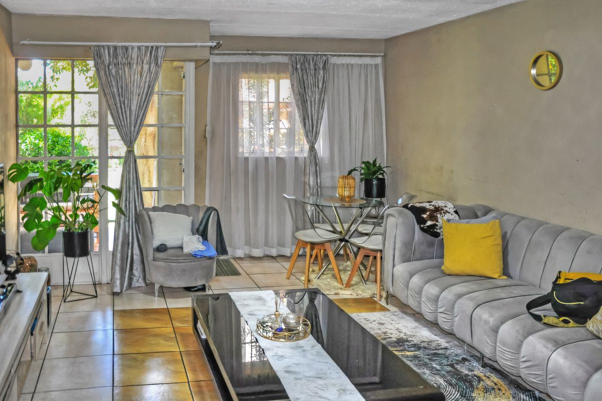A living room featuring tiled flooring, a large window, and a french door leading to an outdoor area.