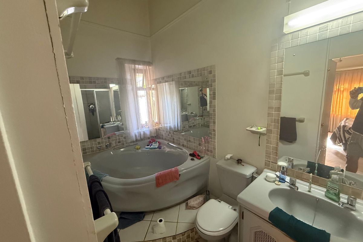 A dated bathroom featuring a corner bathtub, vanity cabinet with basin, and toilet, requiring cosmetic updates to modernize the space.