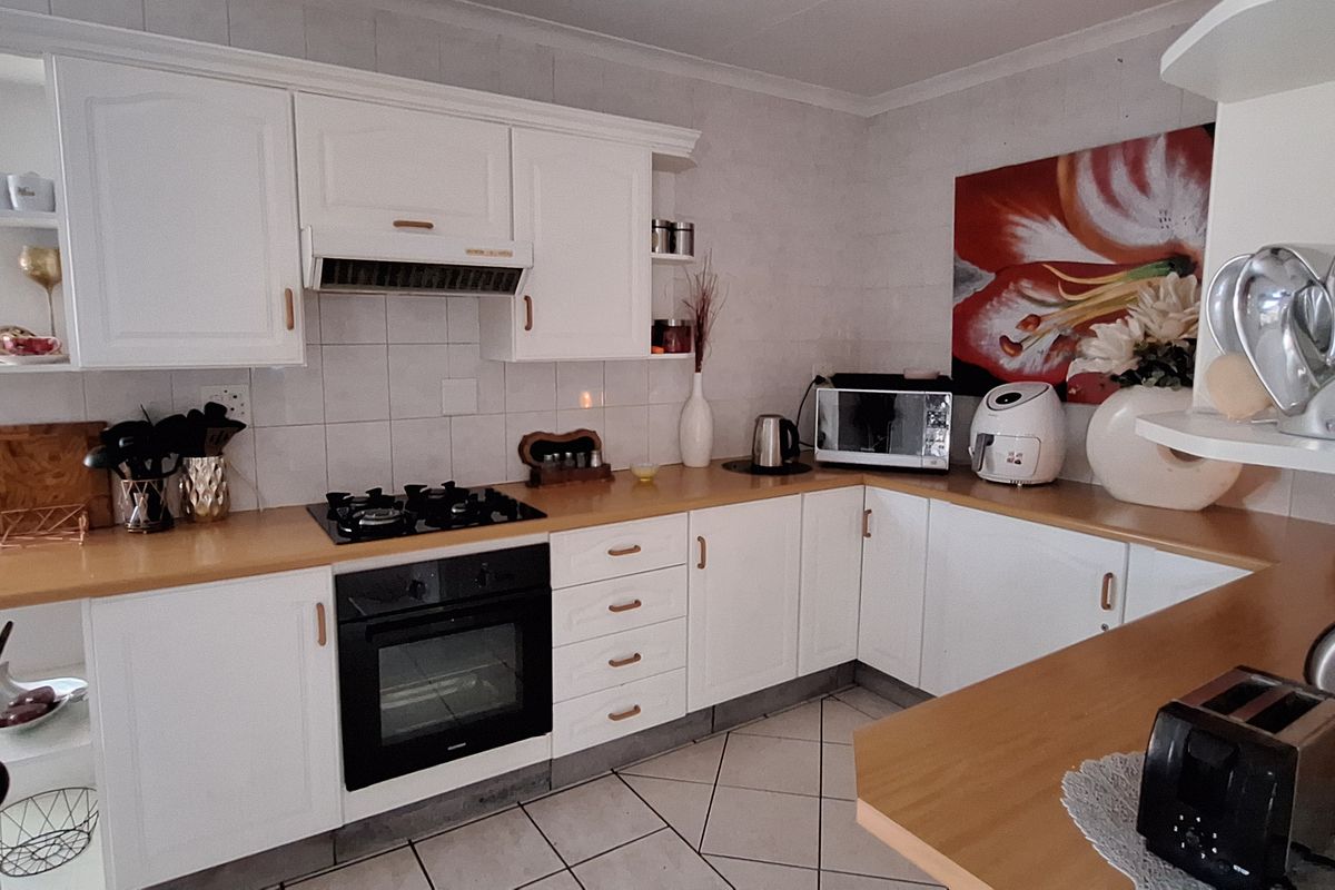 A functional kitchen featuring white cabinetry, a gas hob, an electric oven, and light-toned laminate countertops with a tiled backsplash.
