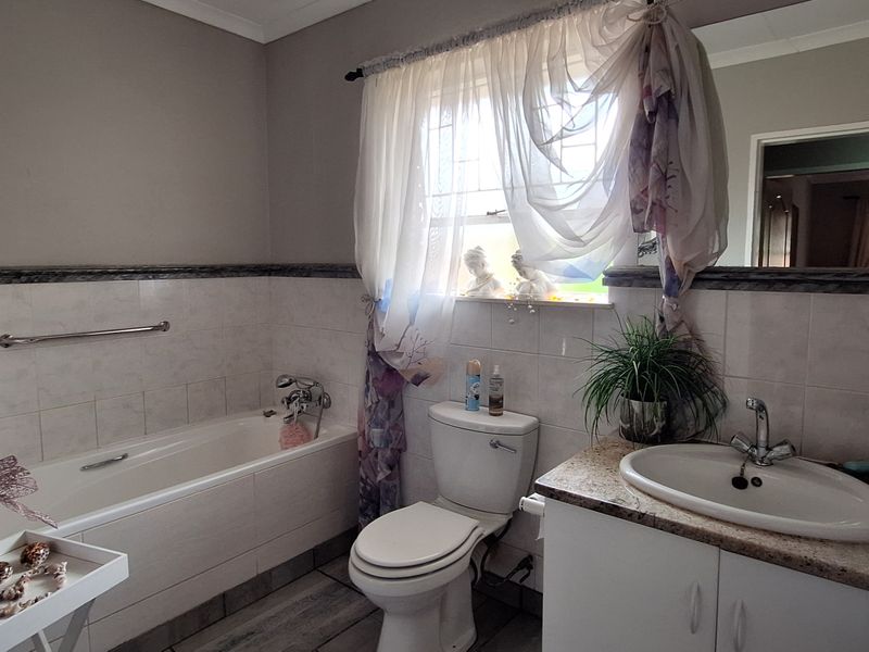 A functional bathroom featuring a built-in vanity with a ceramic basin, a standard bathtub, a toilet, and tiled finishes throughout.