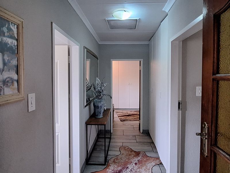 A well-maintained hallway featuring tiled flooring, built-in storage cupboards, and a classic timber door with glass paneling leading to adjacent rooms.