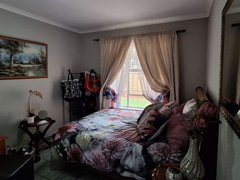 A cozy bedroom featuring tiled flooring and a window dressed with curtains, providing a comfortable and functional living space.