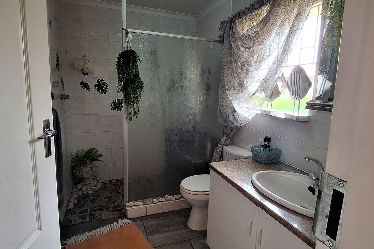 A functional bathroom featuring a shower enclosure, vanity with basin, and toilet, finished with tiled flooring and wall tiles.