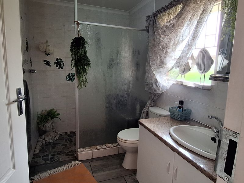 A functional bathroom featuring a shower enclosure, vanity with basin, and toilet, finished with tiled flooring and wall tiles.