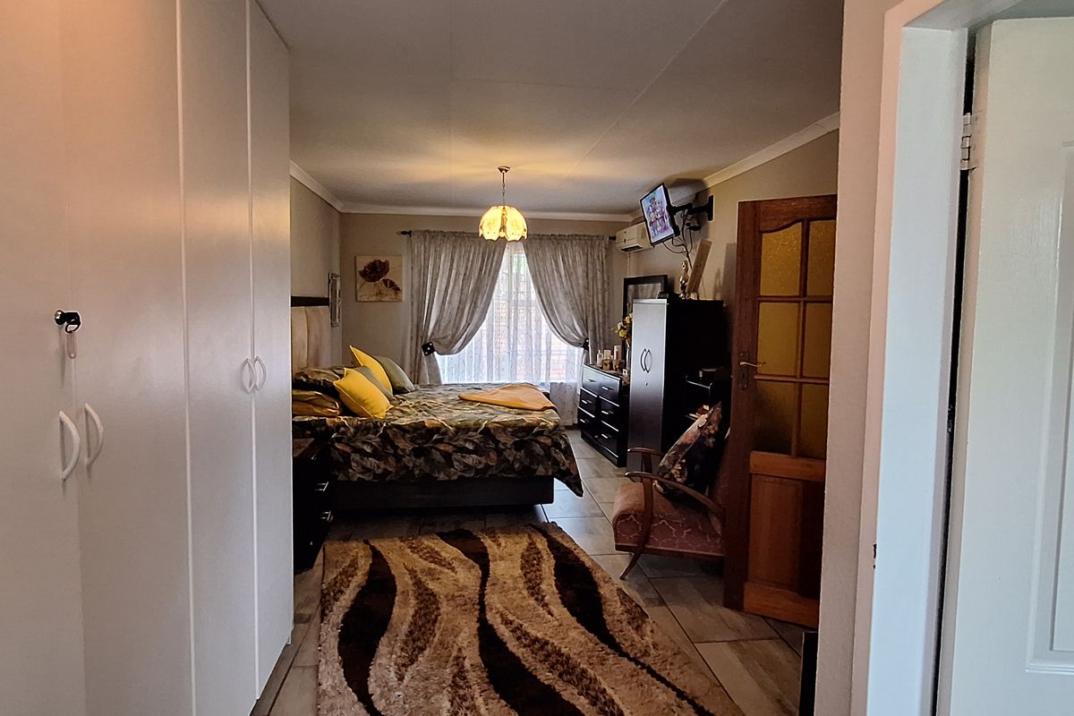 A spacious bedroom featuring built-in cupboards, tiled flooring, and coved ceilings, offering a functional layout with natural light from the window.