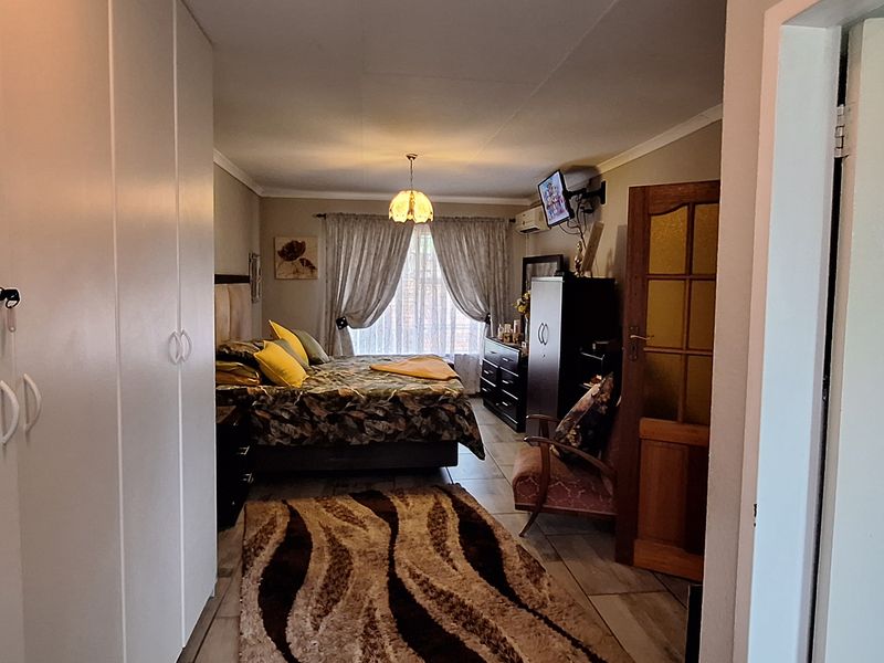 A spacious bedroom featuring built-in cupboards, tiled flooring, and coved ceilings, offering a functional layout with natural light from the window.