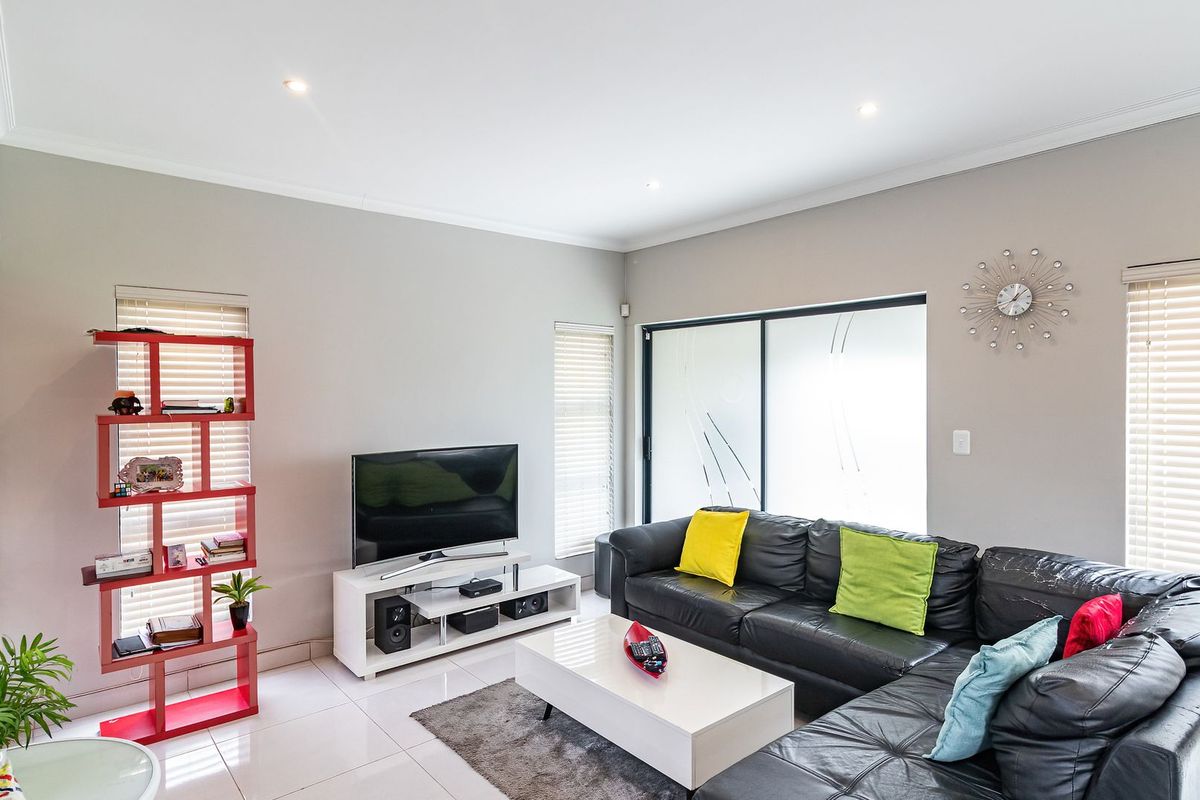 A bright and modern living room featuring tiled flooring, recessed downlights, and large sliding glass doors that provide ample natural light.